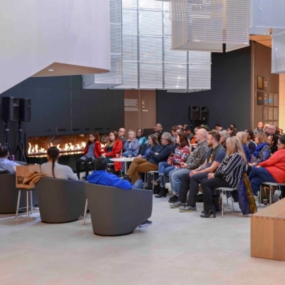 People sit in chairs, gathered around a fireplace at the Remai Modern gallery. 