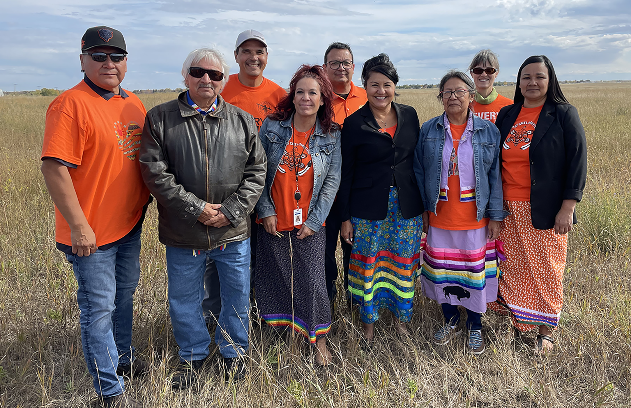 Nine people stand in a field.