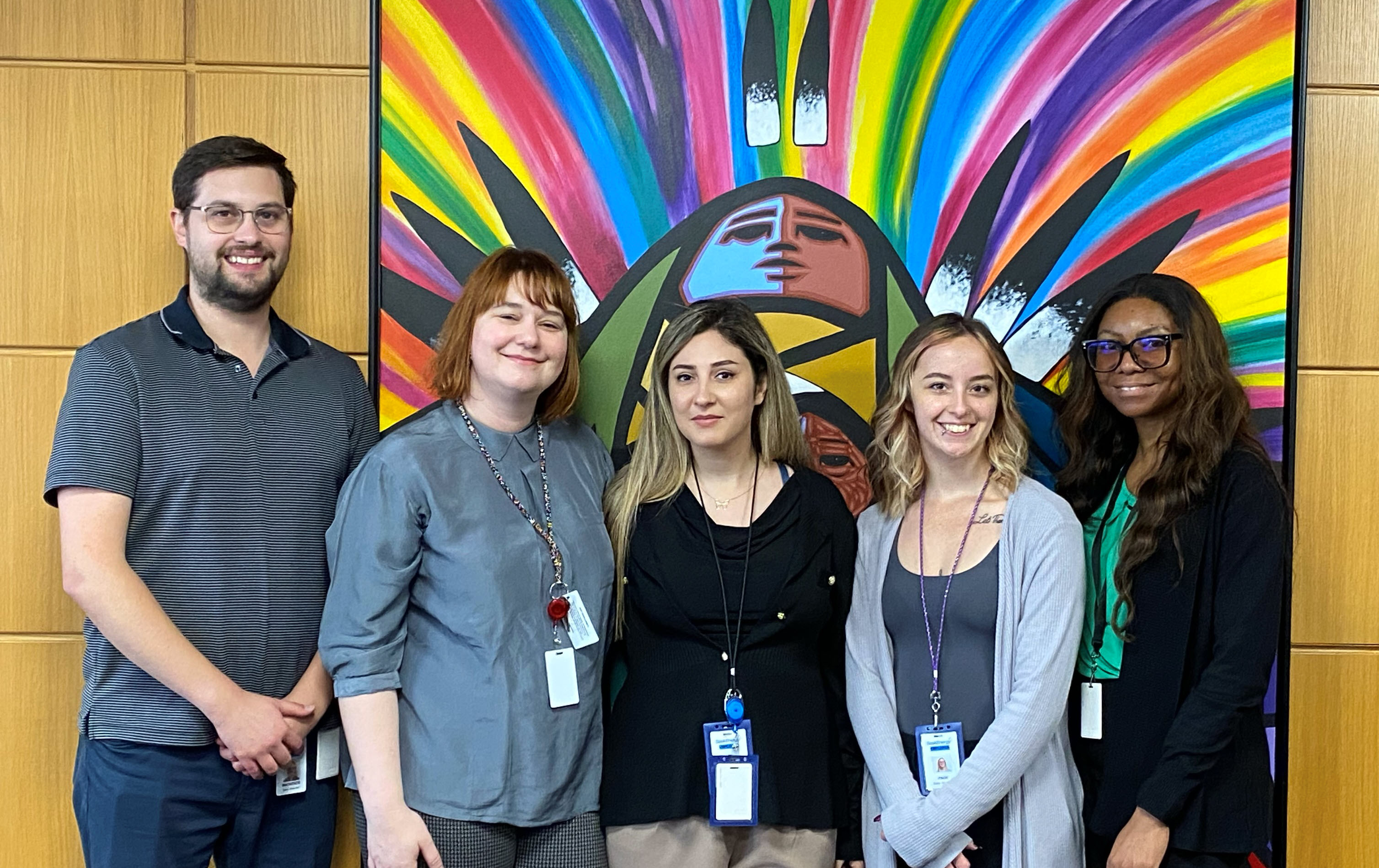 Five people standing in front of a painting