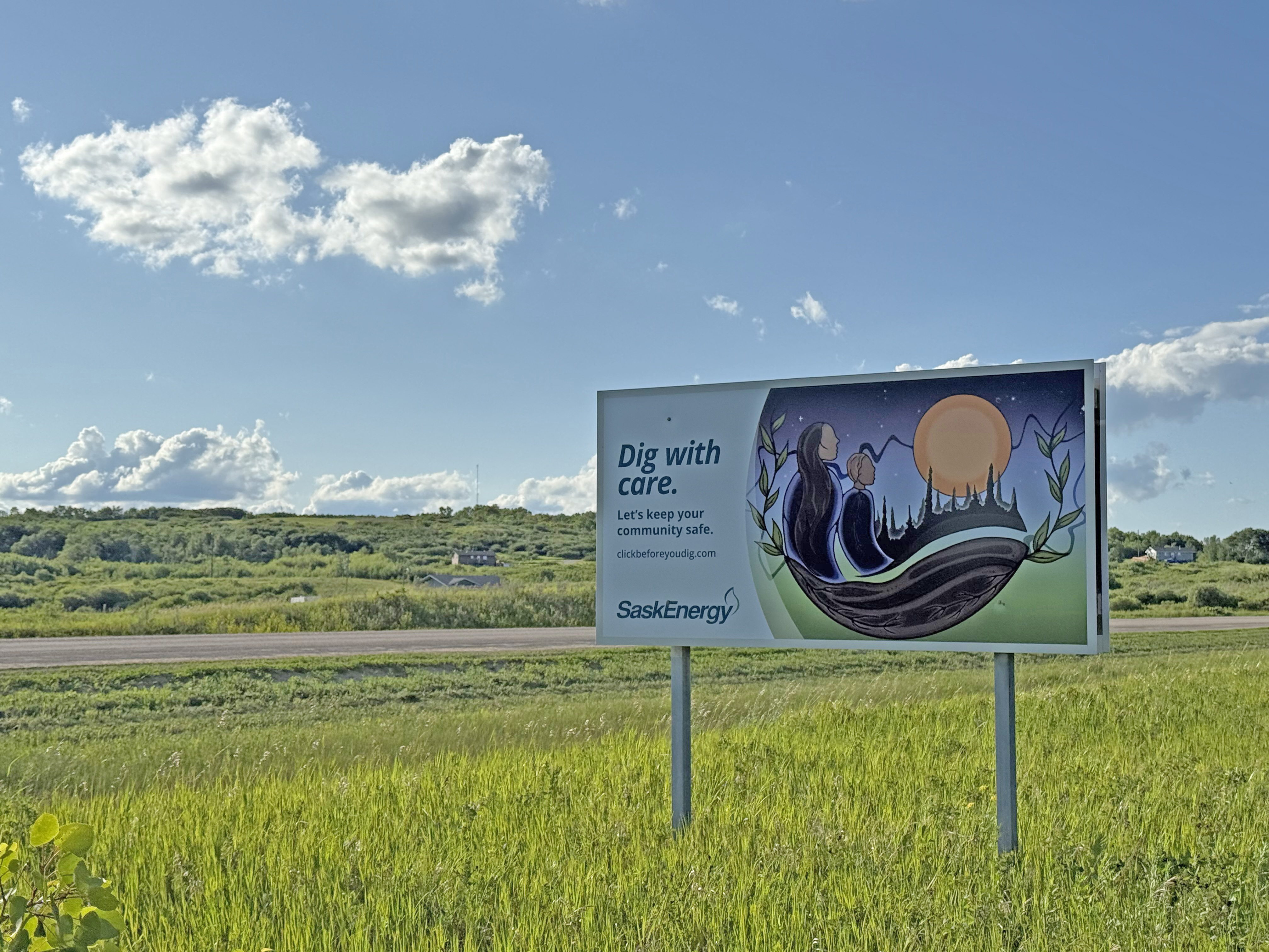 SaskEnergy safety sign with Indigenous art in field.