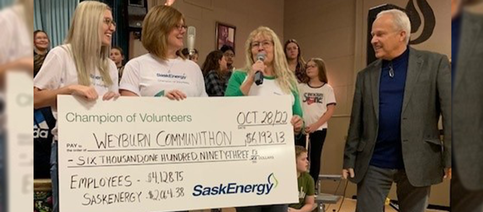 Three SaskEnergy employees hold an oversized cheque.