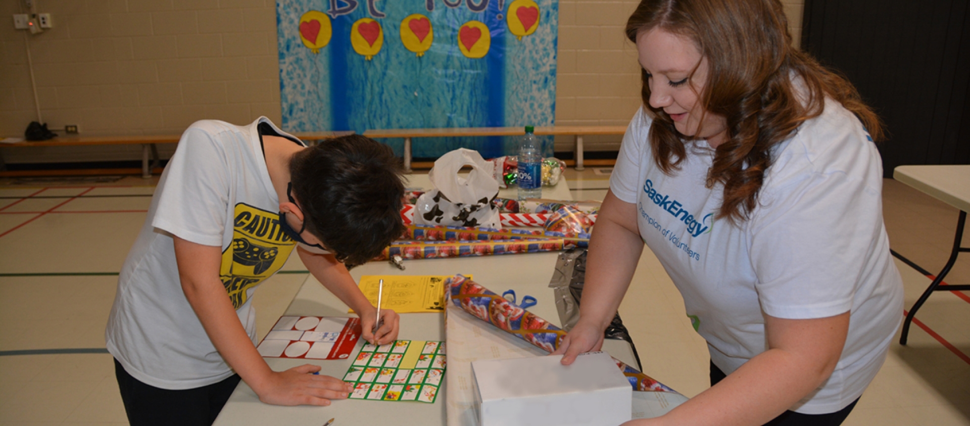 A SaskEnergy employee wraps a giftbox for a student.