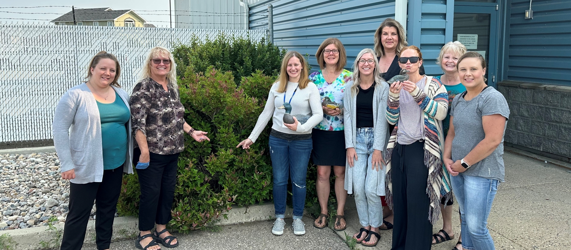 A group of SaskEnergy employees in Weyburn pose next to a bush that a duck made her nest in