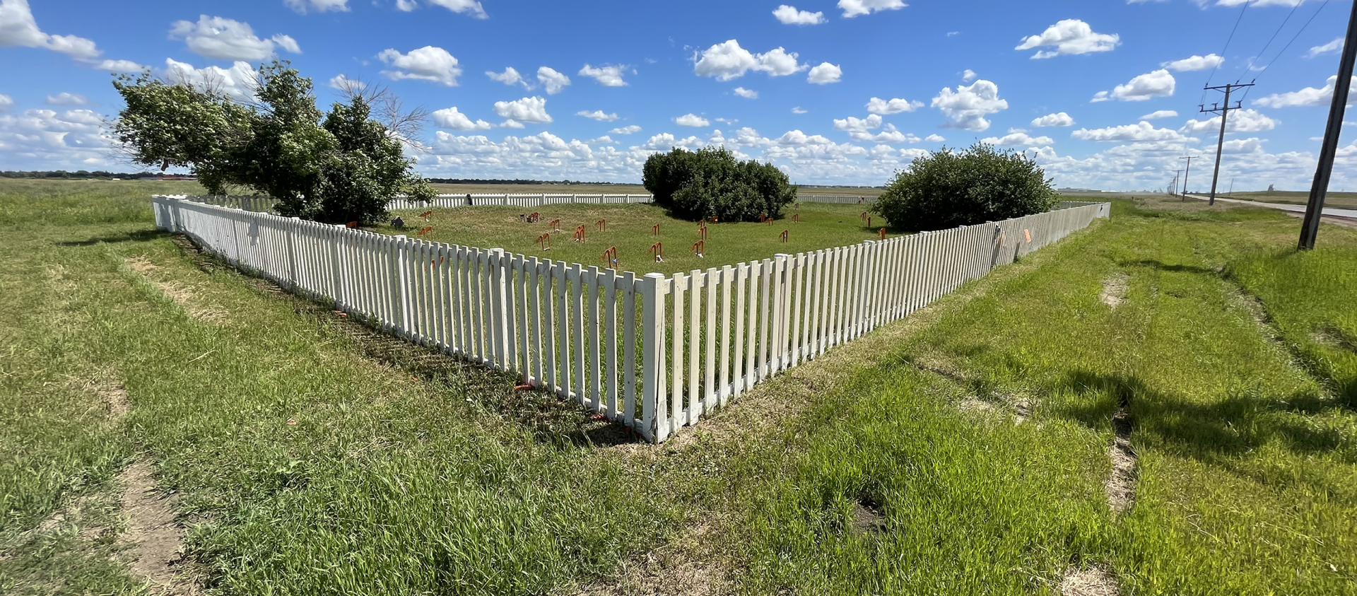 A graveyard outlined by a white fence