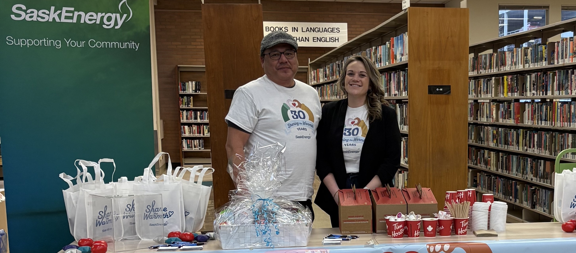 Two people stand by a table and a banner