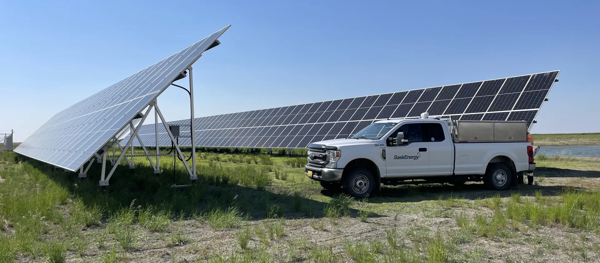 SaskEnergy truck parked by solar panels on a sunny day.