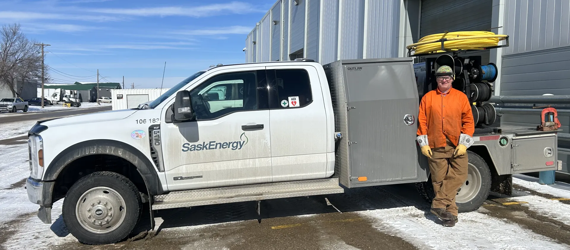 A Pipeline Welder stands in front of a SaskEnergy construction truck