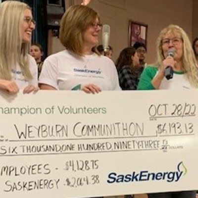 Three SaskEnergy employees hold an oversized cheque.