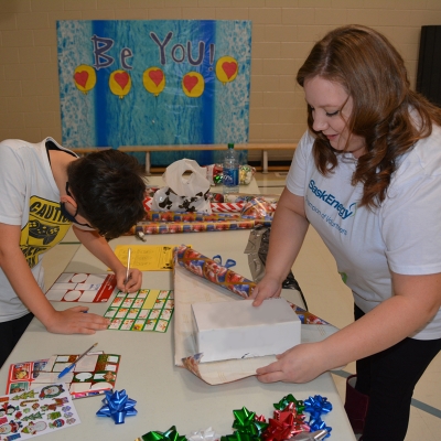 A SaskEnergy employee wraps a giftbox for a student.