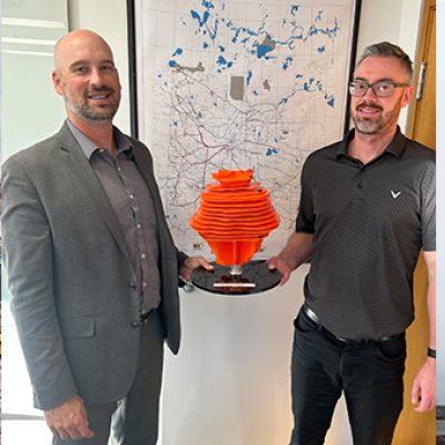 Above ground infrastructure at a storage cavern facility and two men holding a model of a storage cavern