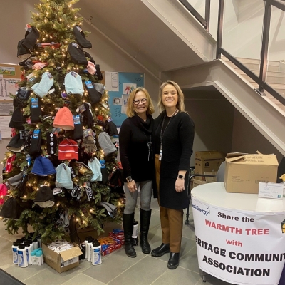 Two people stand next to a Christmas tree. 