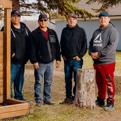 Four men stand in a row outdoors.