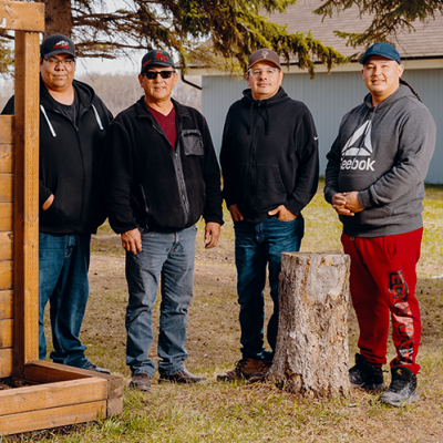 Four men stand in a row outdoors.