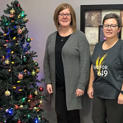 Four people stand near a Christmas tree