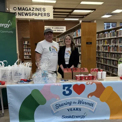 Two people stand by a table and a banner