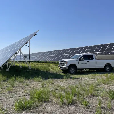 SaskEnergy truck parked by solar panels on a sunny day.