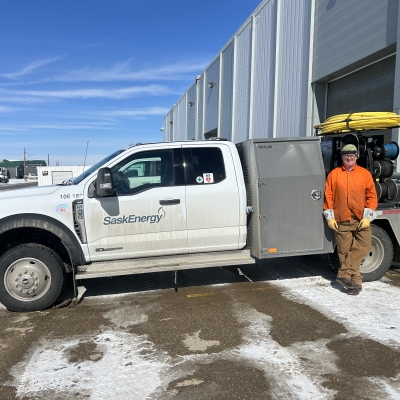 A Pipeline Welder stands in front of a SaskEnergy construction truck