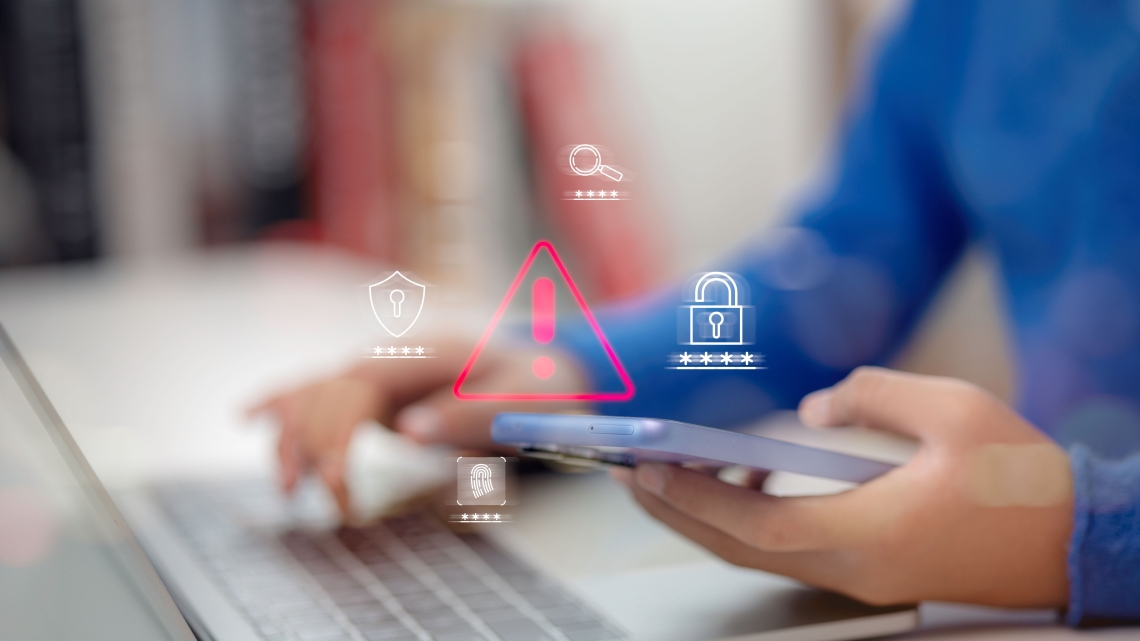 Hands typing at a computer and holding a phone