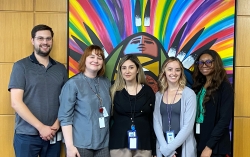 Five people standing in front of a painting