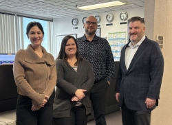 Two women and two men pose for a picture in an office setting.