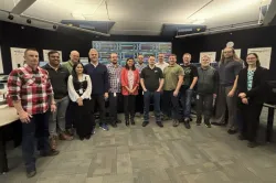 A team of men and women pose for photo.
