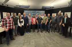 A team of men and women pose for photo.