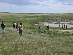 Hikers walking through prairie land.
