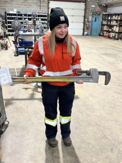 A SaskEnergy Technician poses with a large pipe wrench.