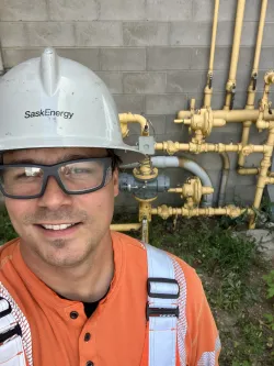 A SaskEnergy Technician stands with gas line visible in the background.