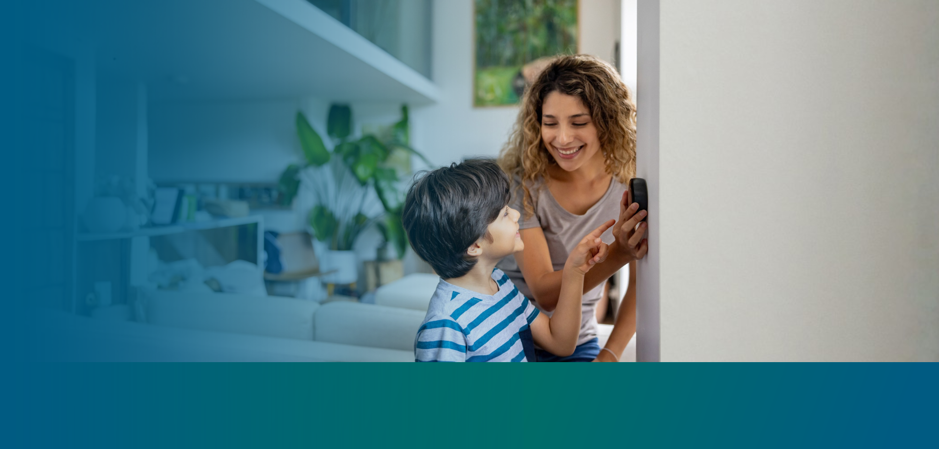 mother and son looking at a smart thermostat on a wall